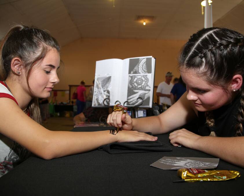 HENNA: Bree Castle, 15 gets a henna tattoo from Mini Nunn, 15 at the Griffith Mind, Body and Soul Festival. Picture: Anthony Stipo.