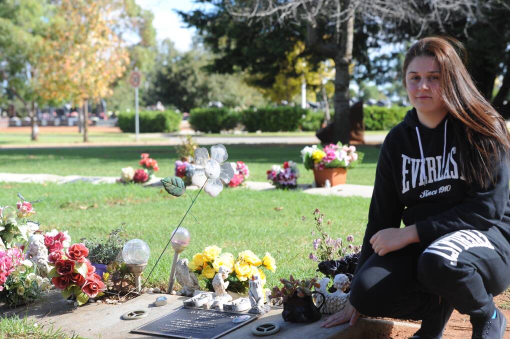 GRIEF: Jessica Taylor pictured at her father's lovingly decorated grave. PHOTO: Hannah Higgins.