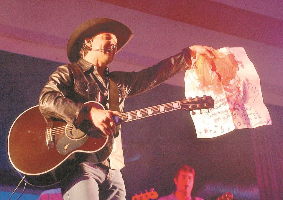CROWD FAVOURITE: Lee Kernaghan with a sign made by a three-year-old fan from Carrathool in his last visit to the city.