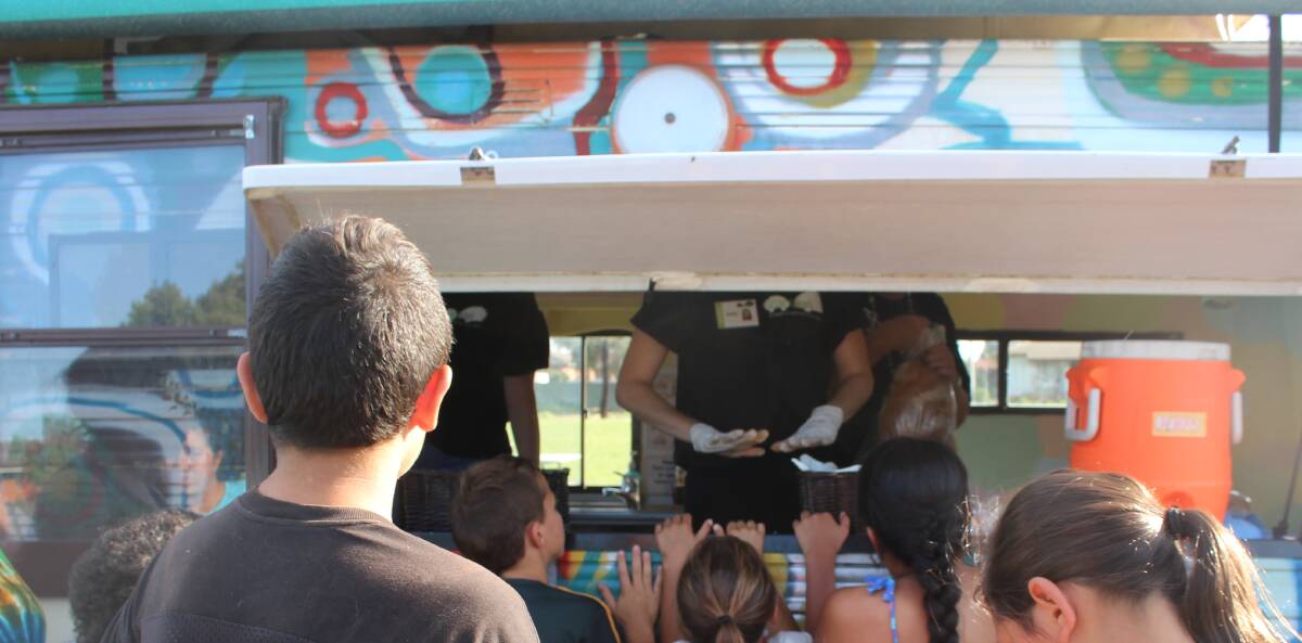 EXCITED: Children line up to receive dinner from Carevan. Carevan provides 120 people per week with meals.