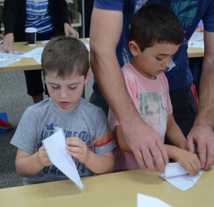 FOCUS: Xavier, 5, and Zachary Spiers, 7, work on their paper aeroplanes at the library last week on Friday. Picture: Ben Jaffrey.