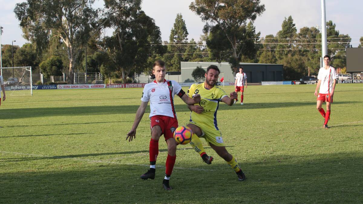 Yoogali FC A's Sam Ciampa fights with Griffith City's Eril Lintmann for possession.