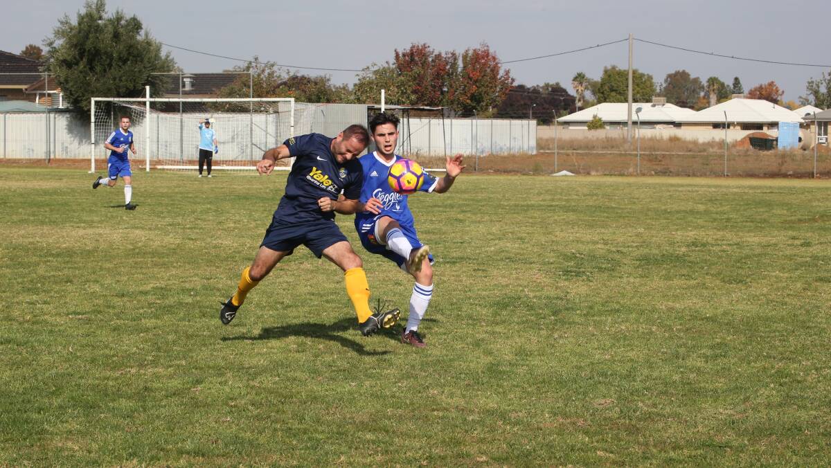 FIGHTING HARD: Hanwood FC Blue's Brad Plos goes into a physical contest with Yoogali SC's Mark Giammini. PHOTO: Anthony Stipo