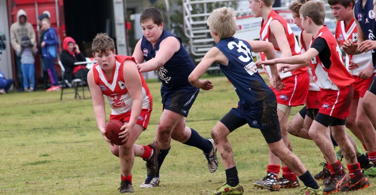 Ben Rowston looks to get clear of the pack in his under 13's AFL match.