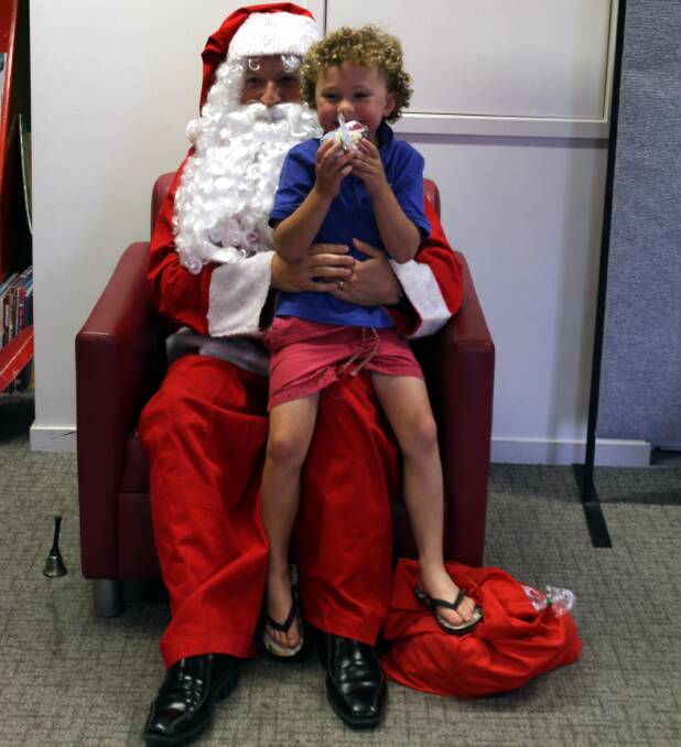 Kade McLennan, 6, loves getting up close and personal with Santa Claus at the Leeton library's Christmas-themed storytime. 