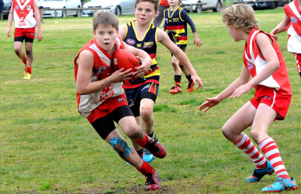 DETERMINED: Olivia Bartter tucks the Sherrin under his arm and takes off for the Griffith Swans Red under 11s. Picture: Wendy Simpkin