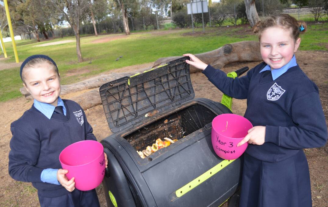 SMILES: Ruby Badoco and Ella Solari help fill up the compost for the vegetable garden.