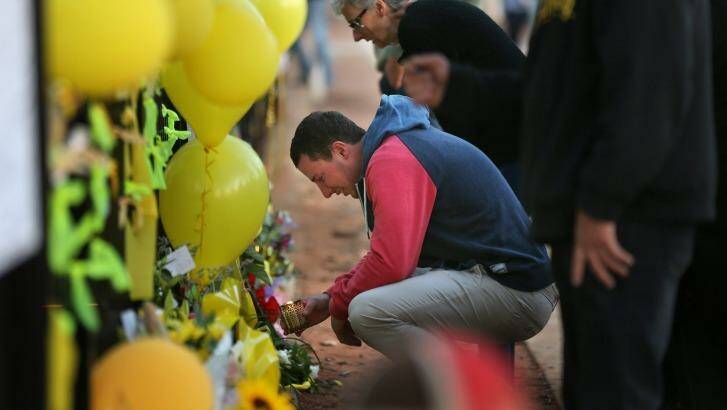 Stephanie Scott's fiance Aaron Leeson-Woolley visits a floral memorial on the gates of the Leeton High School. Photo: Kate Geraghty