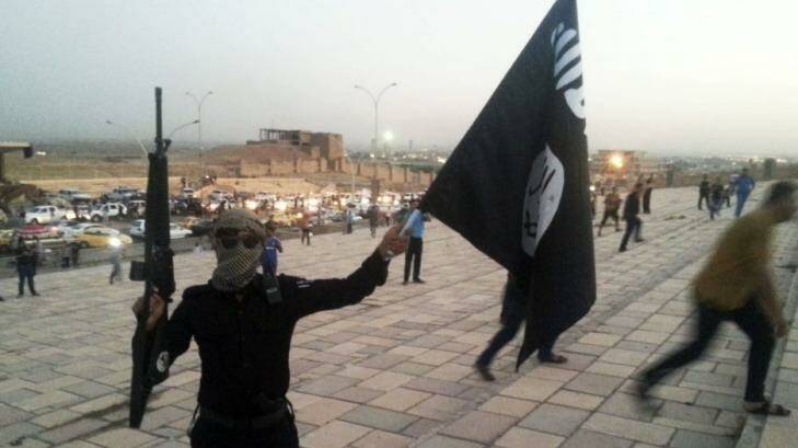 An ISIL militant holds an ISIL flag and weapon in the Iraqi city of Mosul on June 23, 2014.