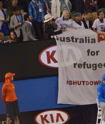 Protesters unfurl a banner during the men's final, drawing attention to the plight of refugees on Manus Island.  Photo: Joe Armao