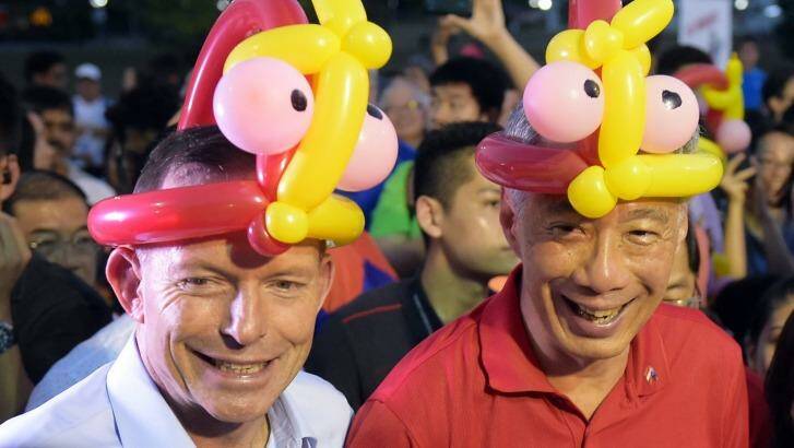 Prime Minister Tony Abbott and Singapore Prime Minister Lee Hsien Loong don balloon hats at Bishan Park.