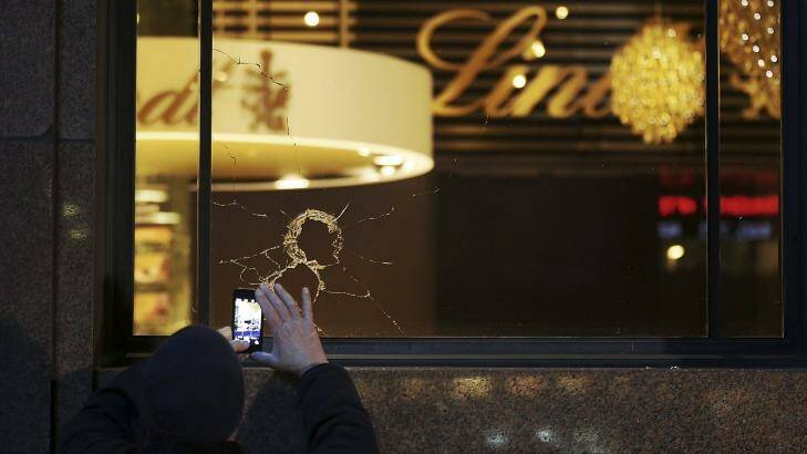 A man takes a photo of the broken glass from vandalised windows at the Lindt cafe in Martin Place, Sydney. Photo: Kate Geraghty