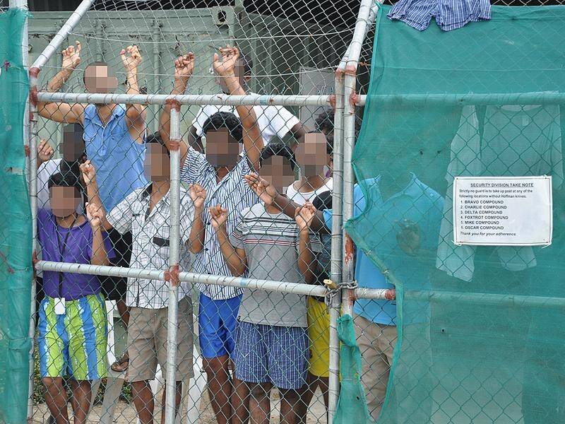 Asylum seekers staring at media from behind a fence at the Manus Island detention centre (file).