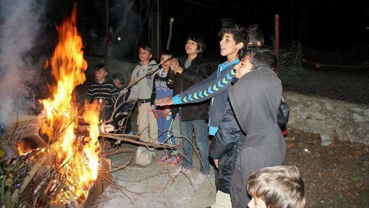 Refugees at a camp in Serres use foraged branches to build a fire. Photo: Hashim Kheri Kutu