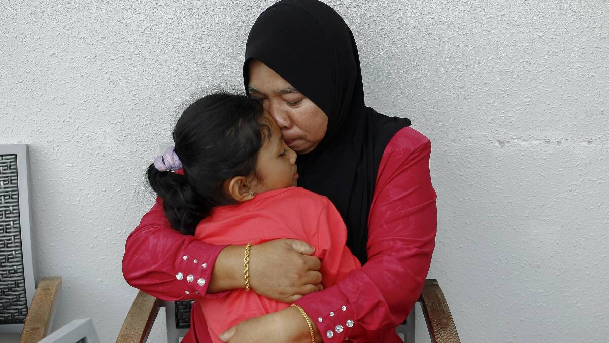 Rosila Abu Samah, 50, and her daughter Kaiyisah Selamat, 8, the mother and sister of flight engineer Mohd Khairul Amri Selamat who was on board missing Malaysia Airlines flight MH370, hug each other during an interview inside the hotel where they and other relatives of the passengers of the missing Boeing 777-200ER are staying in Putrajaya March 20, 2014. Photo: Reuters.