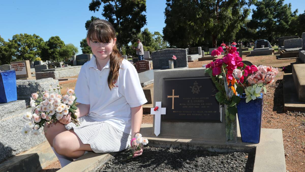 Anzac Day 2014, Jenna Oakes 11, placing a flower on her grandfather's grave.