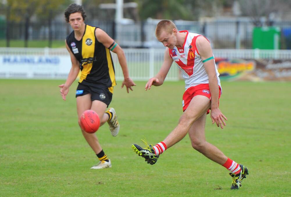 KICK AND RUSH: Griffith's James Taylor boots to advantage on Saturday as Jake Gunning of the Wagga Tigers gives chase.