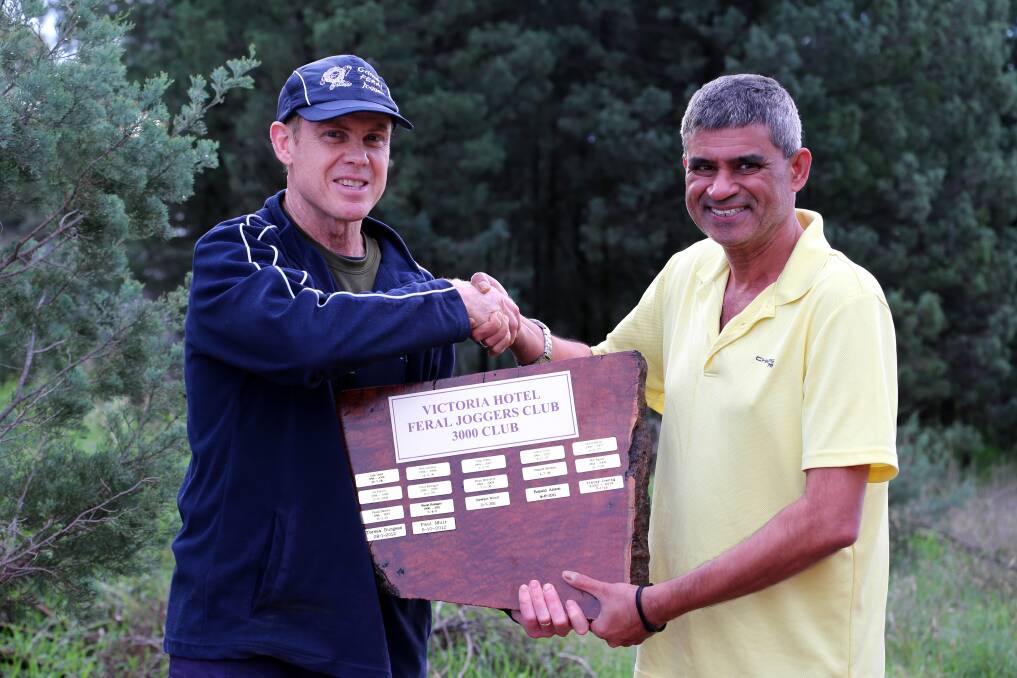 THE HOLY GRAIL: Paul Muir hands Griffith Feral Joggers veteran Arun Tiwari the Wardle Waddle trophy after he joined the illustrious 3000km club on Saturday.