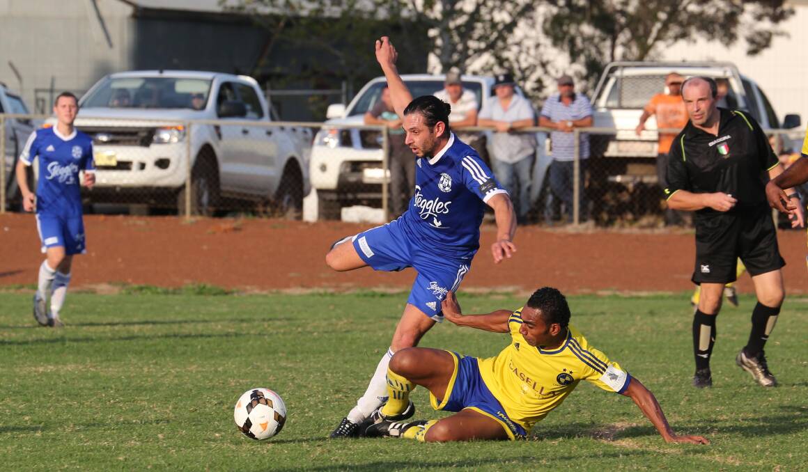 BATTLE OF ATTRITION: Hanwood FC's Joey Schirripa tries to keep his balance as YFC's Taniela Waqa slides in with this challenge yesterday at Noe Santolin Oval. Picture: Anthony Stipo