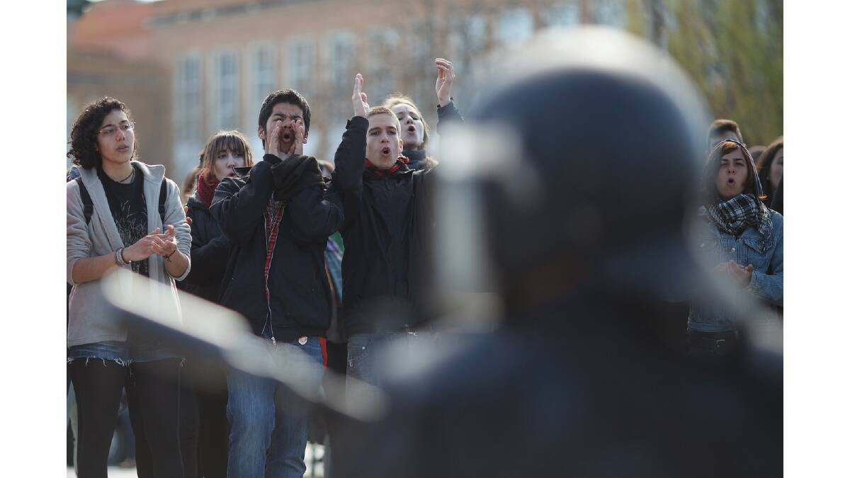 Students shout slogans outside a campus building in support of arrested students as riot police stand guard during a protest against the government's education reforms and cutbacks in university grants and staffing in Campus Ciudad Universitaria on March 26, 2014 in Madrid, Spain. Photo: Getty Images.