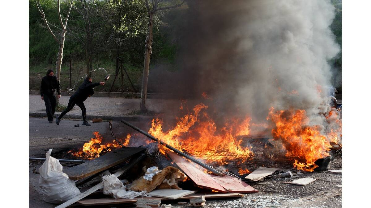 A protester throws a bottle into a burning barricade during a protest against the government's education reforms and cutbacks in university grants and staffing in Campus Ciudad Universitaria on March 26, 2014 in Madrid, Spain. Photo: Getty Images.