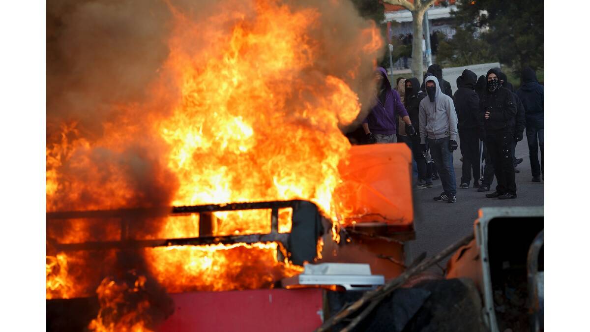 Protesters stand behind a burning barricade during a protest against the government's education reforms and cutbacks in university grants and staffing in Campus Ciudad Universitaria on March 26, 2014 in Madrid, Spain. Photo: Getty Images.