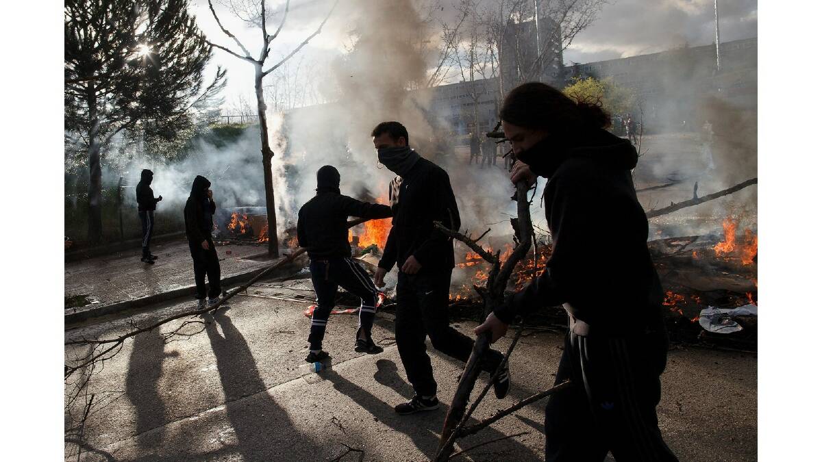 Students throw a branches into a burning barricade during a protest against the government's education reforms and cutbacks in university grants and staffing in Campus Ciudad Universitaria on March 26, 2014 in Madrid, Spain. Photo: Getty Images.