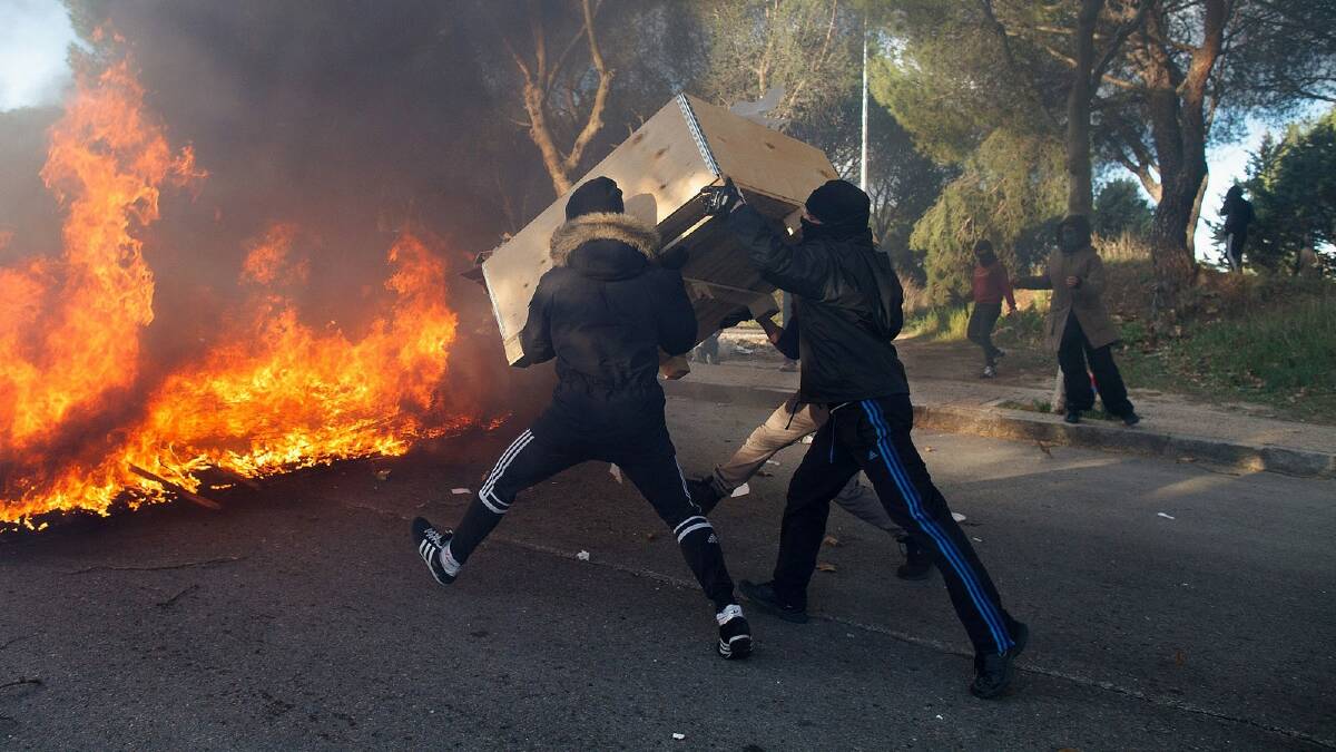 Students throw a wooden box into a burning barricade during a protest against the government's education reforms and cutbacks in university grants and staffing in Campus Ciudad Universitaria on March 26, 2014 in Madrid, Spain. Photo: Getty Images.