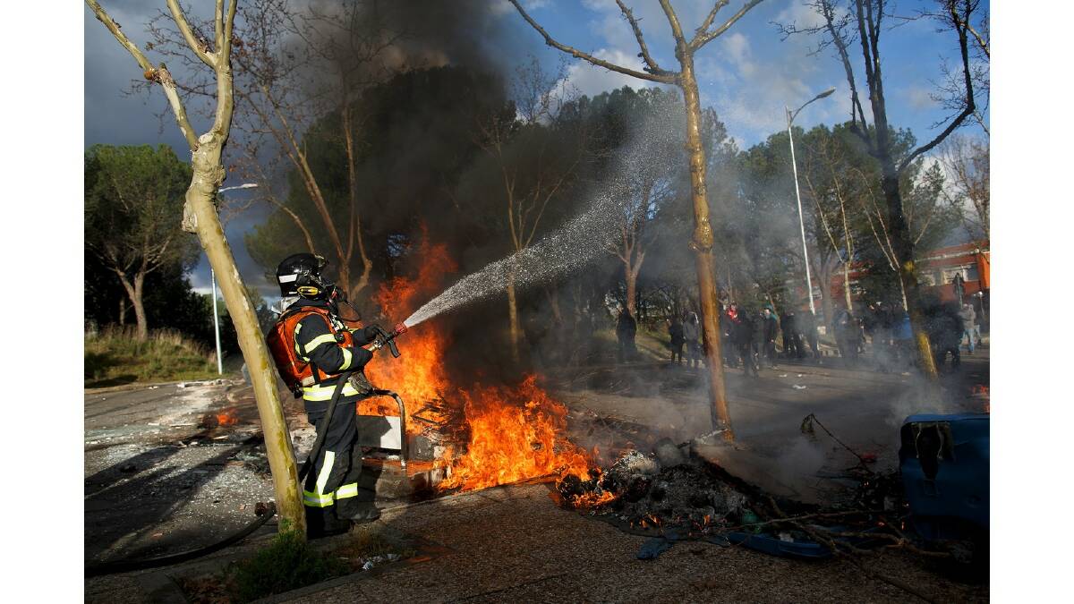 A fireman extinguishes burning barricade surrounding during a protest against the government's education reforms and cutbacks in university grants and staffing in Campus Ciudad Universitaria on March 26, 2014 in Madrid, Spain. Photo: Getty Images.