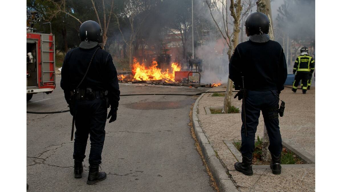 Riot police stand near a burning barricade during a protest against the government's education reforms and cutbacks in university grants and staffing in Campus Ciudad Universitaria on March 26, 2014 in Madrid, Spain. Photo: Getty Images.