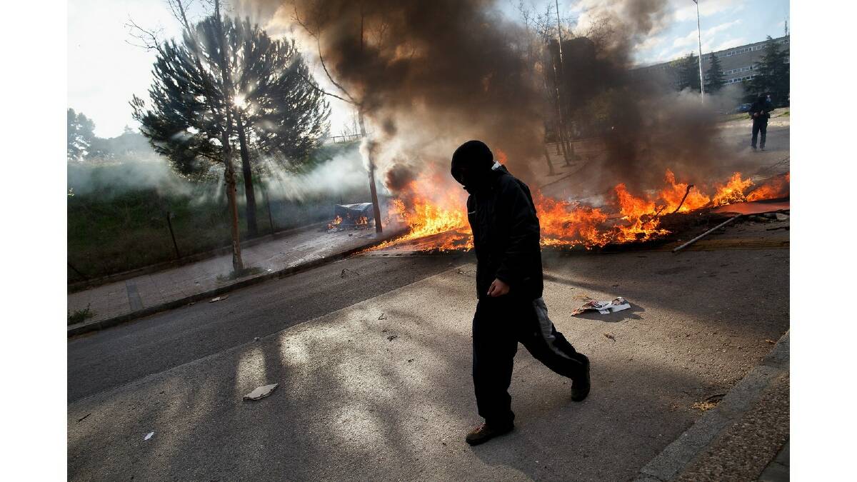 A protester walks by a burning barricade during a protest against the government's education reforms and cutbacks in university grants and staffing in Campus Ciudad Universitaria on March 26, 2014 in Madrid, Spain. Photo: Getty Images.