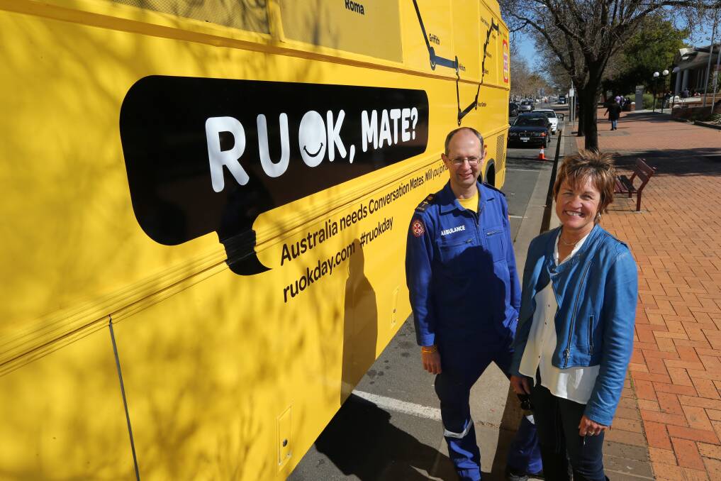 R U OK?: NSW Farmers Griffith branch president Helen Dalton and NSW Ambulance senior chaplain Paul McFarlane in from of the yellow R U OK bus at Memorial Park.