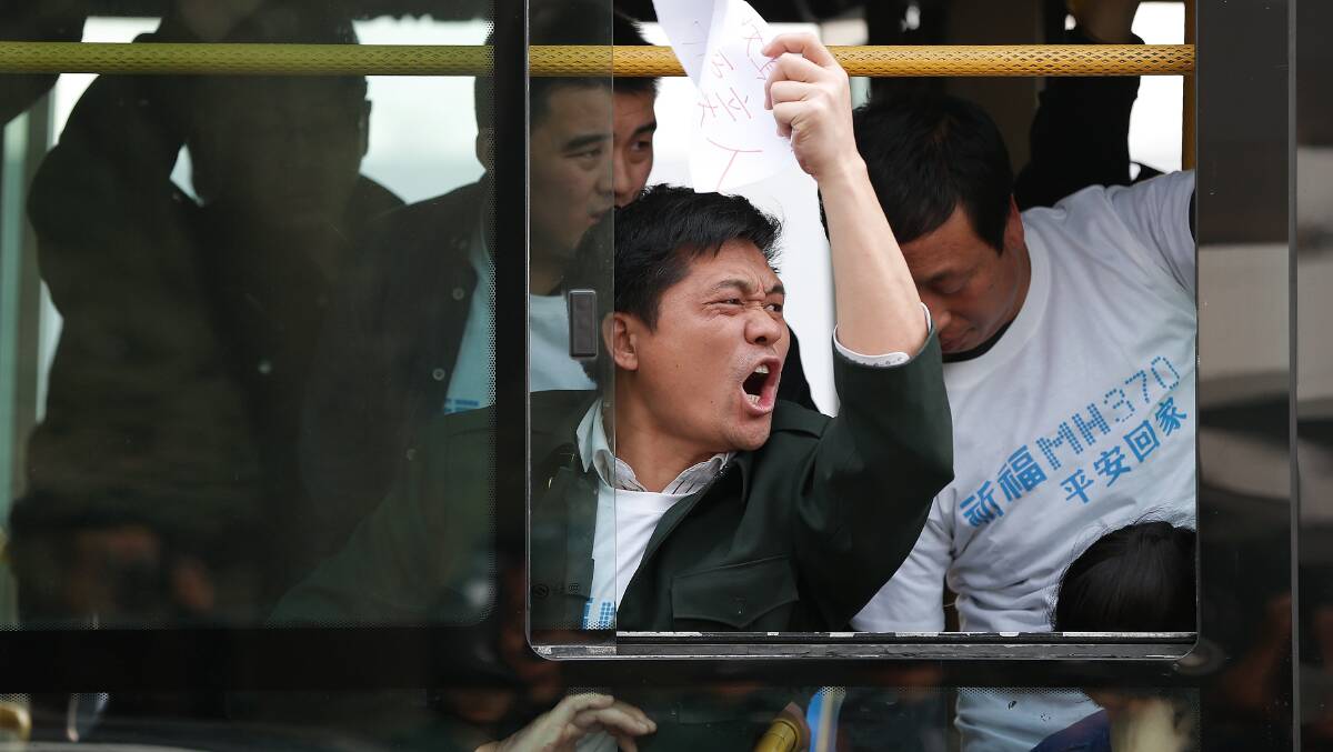Chinese relatives of the flight MH370 gesture in protest as they sit on the bus waiting to go to the Malaysian embassy on March 25, 2014 in Beijing, China. Hundreds of protesters, including many relatives of missing flight MH370 passengers, marched on the Malaysian Embassy in Beijing demanding answers from Malaysian authorities about the fate of the flight. Picture: Getty