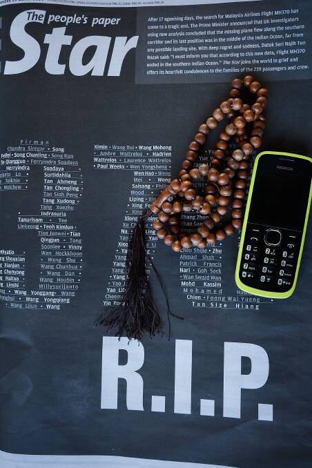 Prayer beads and a handphone owned by a family member of MH370 victim, sits on top of a front page of Kuala Lumpur local newspaper, The Star on March 25. Picture: Getty