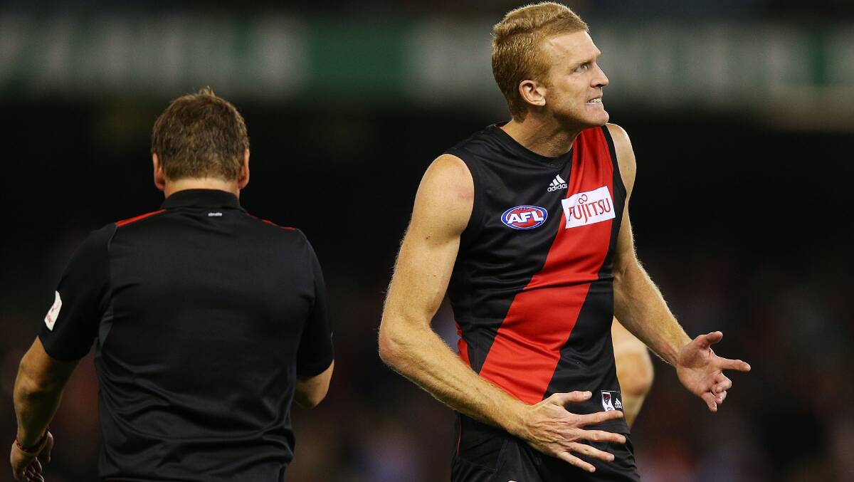 Bombers coach Mark Thompson walks on to the ground as Dustin Fletcher, of the Bombers, reacts after their defeat during the AFL Round two match between the Essendon Bombers and the Hawthorn HawksPicture: Getty