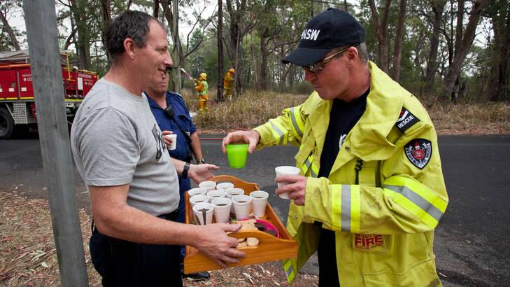 Grateful: A resident offers refreshments to exhausted firefighters and police officers. Photo: Geoff Jones