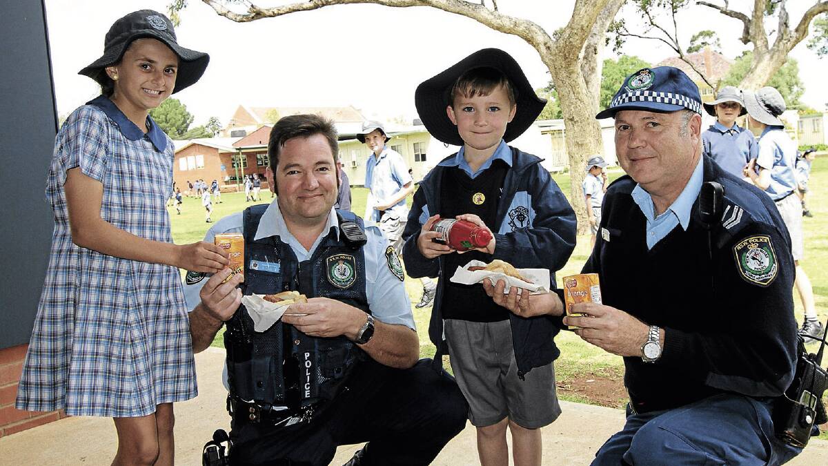 SPECIAL THANKS: Abby Favell, 11, Senior Constable William English, Hamish Crockett, 5, and Senior Constable Tim Lockwood enjoy a sausage during St Pat’s Police Legacy Day sausage sizzle last Wednesday. 	Picture: Anthony Stipo