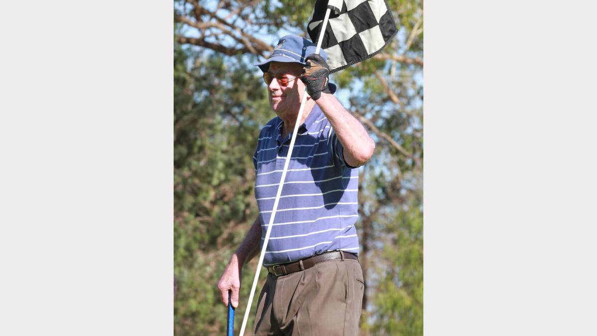 Bill Brown holds the flag waiting for his partner to putt. Picture: Anthony Stipo