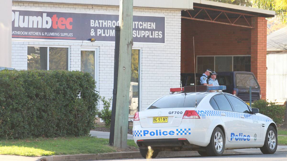 UNDER THE GUN: Two police stand guard at the Collier Street clubhouse of the Vikings outlaw motorcycle gang in Griffith on Wednesday. Police seized cash and drugs from the clubhouse during an investigation.