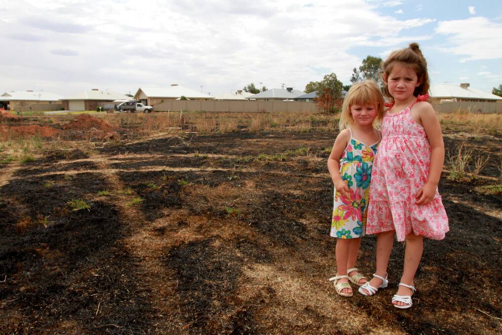 Madeline and Chelsea Brown stare at the burnt grass just outside their home on Walla Avenue, Griffith.