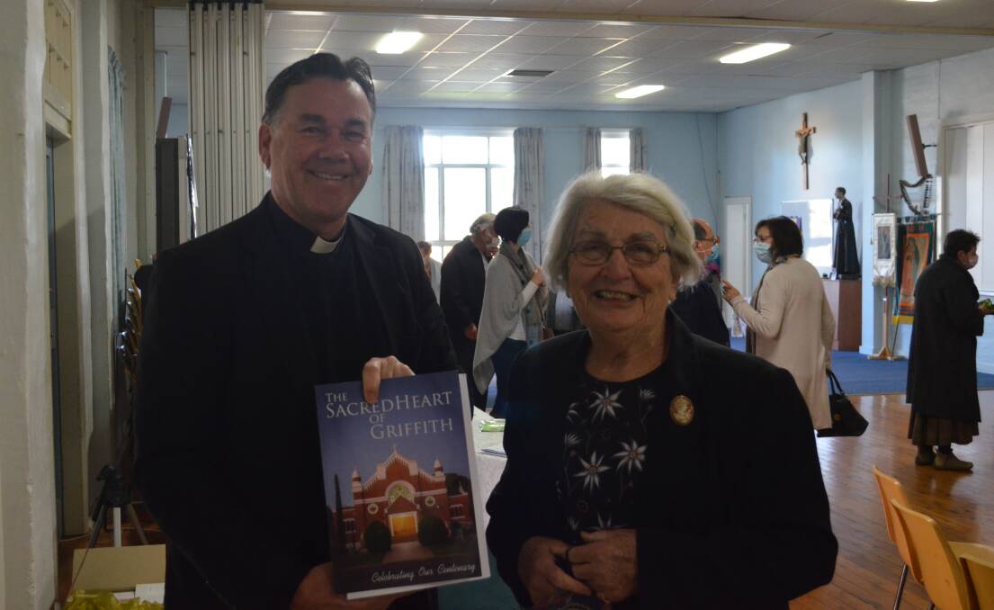 100 YEARS: Father Andrew Grace and Zita Denholm with the book "The Sacred Heart of Griffith," chronicling a century of the Sacred Heart church. PHOTO: Cai Holroyd
