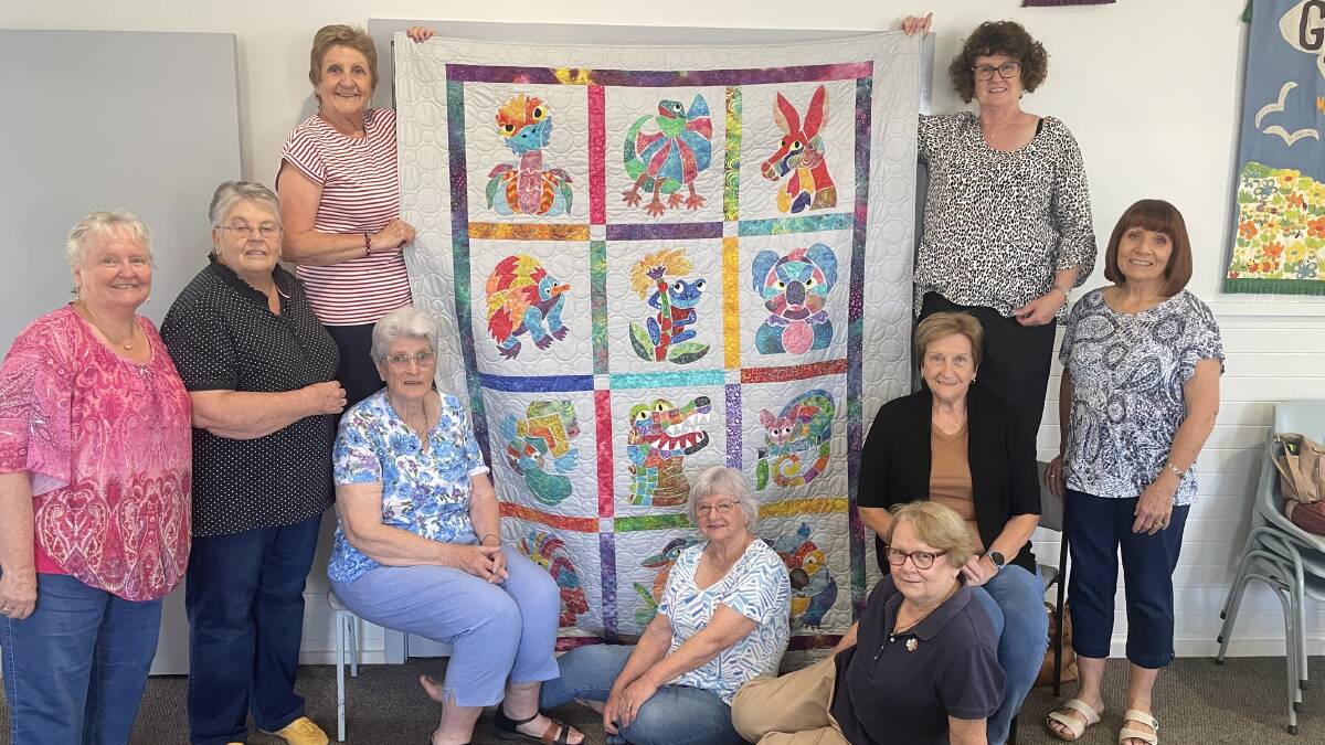 Members of the Murrumbidgee Country Quilters: Robyn McKinnon, Judith Lodding, Maree Smith, Gaynor Clements, Jenny Bamford, Joyce Moorhouse, Robyn Graham, Janelle Violi and Trish Toskin pictured with the main prize to be raffled at the exhibition. Photo Allan Wilson.
