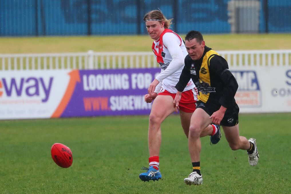 TOUGH CONDITIONS: Griffith's Patrick Payne and Tiger Nick Ryan chase the ball at a sodden Robertson Oval on Saturday. Picture: Emma Hillier