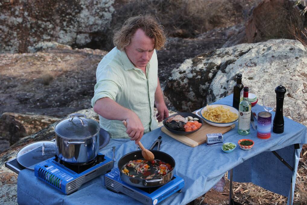 HEATING UP HERMITS CAVE:  Adrian Richardson from Good Chef, Bad Chef, cooking up a storm on a rocky ledge at Hermit's Cave. Picture: Anthony Stipo.