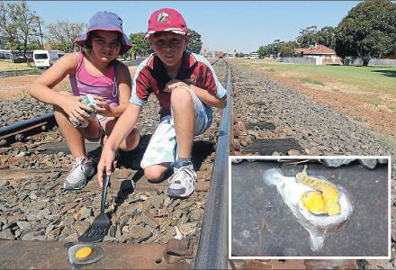 2014: Sam, 11 and Tara Robinson, 10, fry an egg on a railway track on Wednesday. Pictures: Anthony Stipo