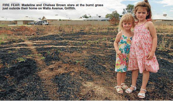 2013: Madeline and Chelsea Brown stare at the burnt grass just outside their home on Walla Avenue, Griffith.