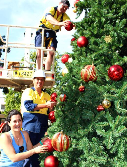 2013: Community Christmas Tree committee member Sonia Callipari, council parks and gardens staff members Tony Romeo and Joel Sartor decorate the big tree in Memorial Park.