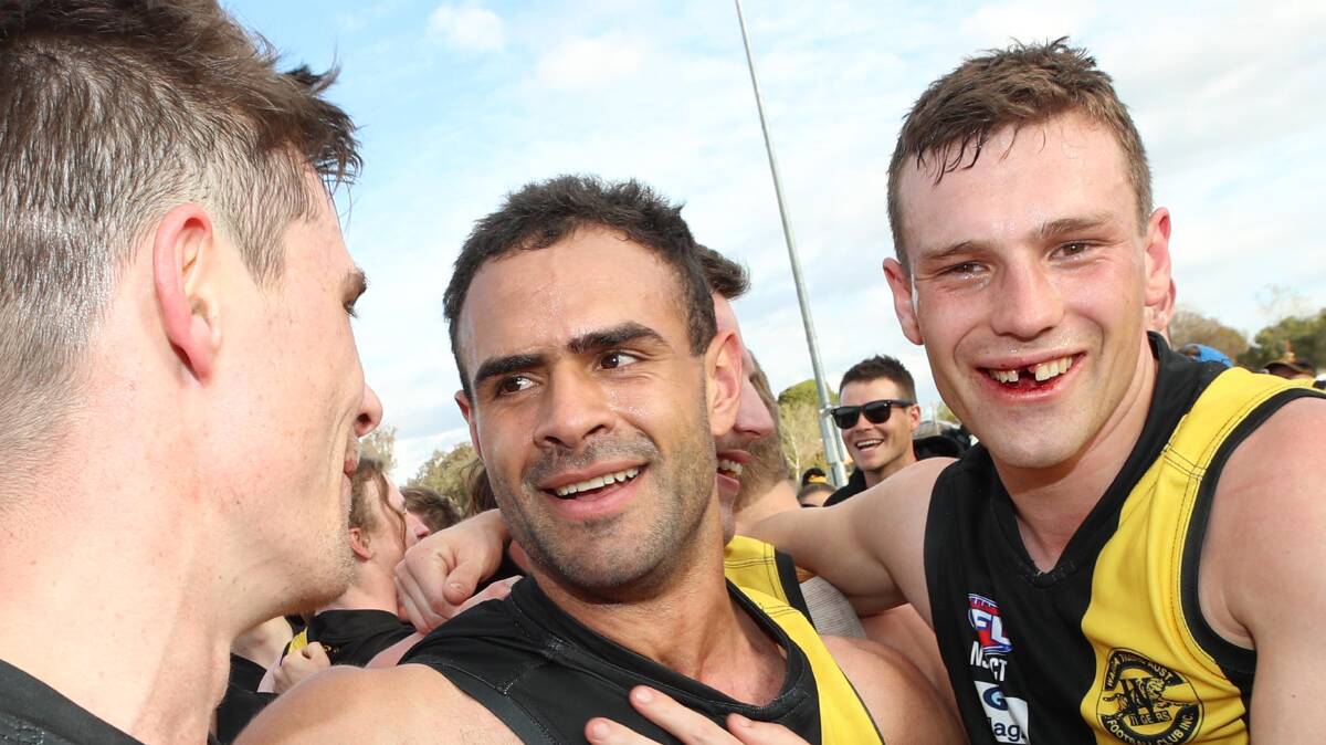 Tom Keogh celebrates Wagga Tigers' premiership success with Jesse Manton without a front tooth.