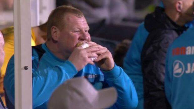 Tucking in: Sutton United reserve goalkeeper Wayne Shaw eats a pie in the dug-out during the game against Arsenal. Photo: BBC