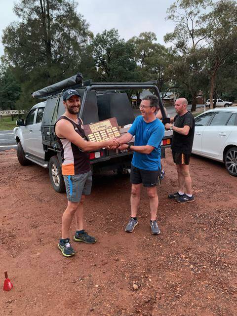 CLOCKING KILOMETRES: Simon Fattore hands on the Golden Jogger Shield to Anthony Salmon. PHOTO: Contributed